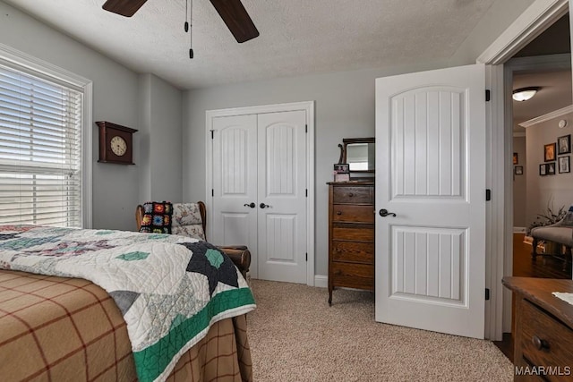 carpeted bedroom with ceiling fan, a closet, and a textured ceiling