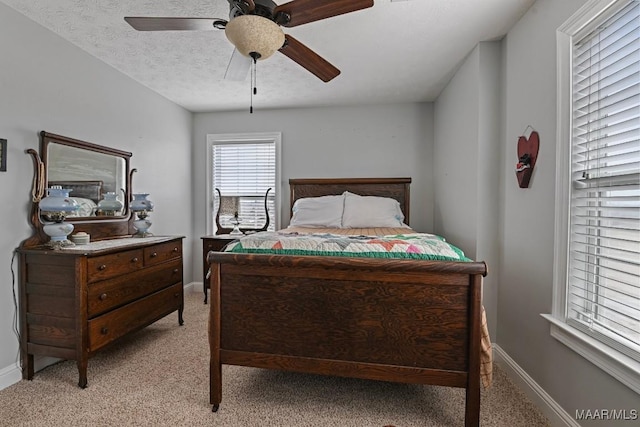 bedroom featuring ceiling fan, light colored carpet, and a textured ceiling