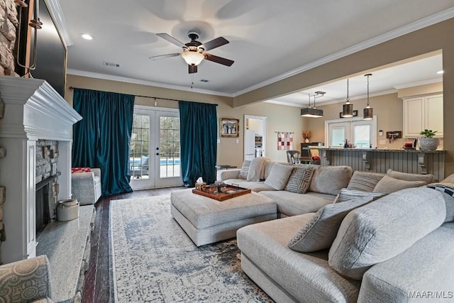 living room featuring a fireplace, crown molding, a wealth of natural light, and french doors