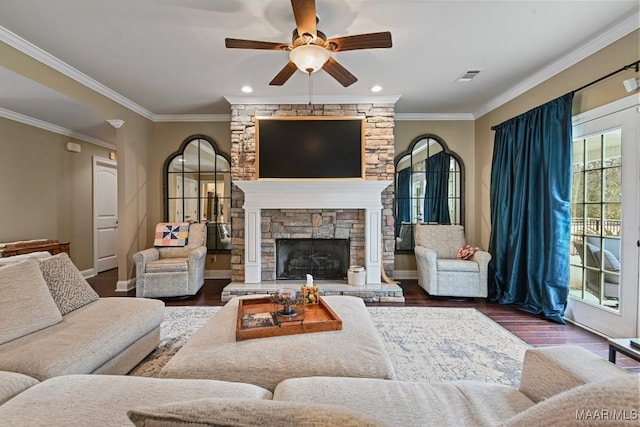 living room with dark wood-type flooring, ceiling fan, ornamental molding, and a fireplace