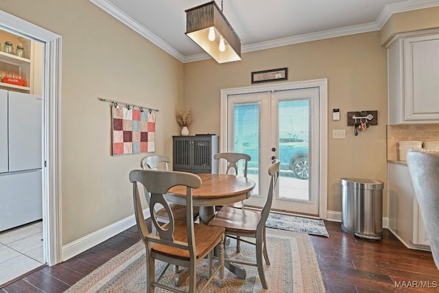 dining area featuring dark wood-type flooring, ornamental molding, and french doors