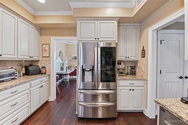 kitchen with white cabinetry, light stone counters, stainless steel fridge, and ornamental molding