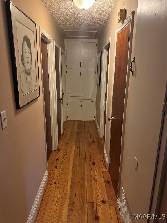 hallway featuring light hardwood / wood-style floors and a textured ceiling