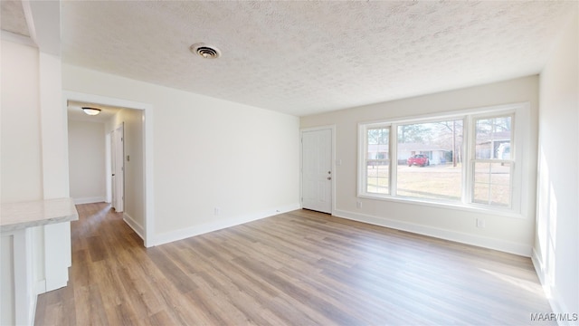 empty room featuring light hardwood / wood-style flooring and a textured ceiling