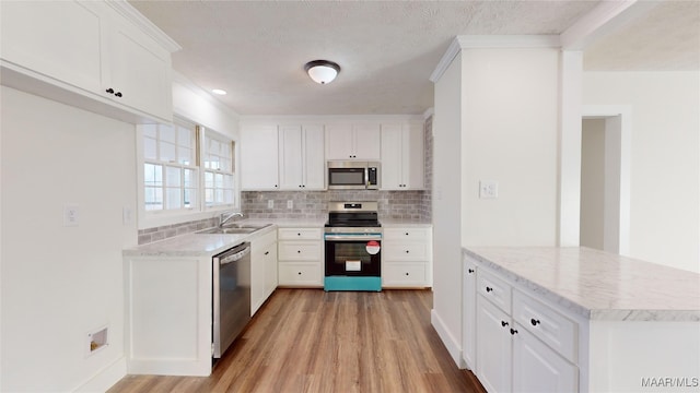 kitchen featuring sink, appliances with stainless steel finishes, white cabinetry, light hardwood / wood-style floors, and decorative backsplash