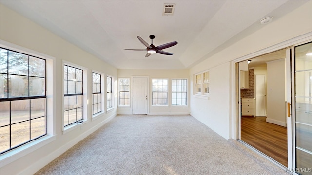 unfurnished sunroom with a tray ceiling, a wealth of natural light, and ceiling fan