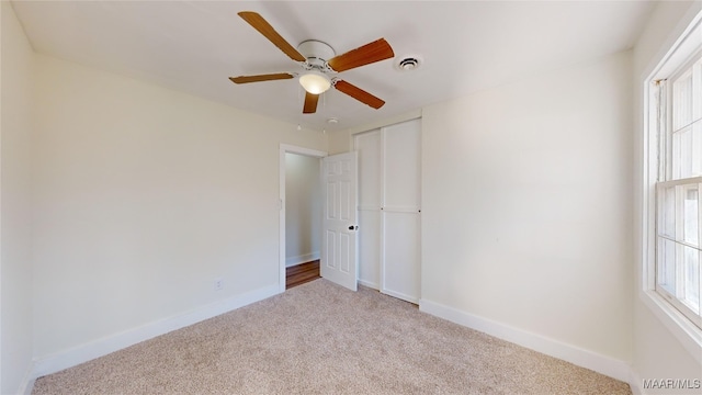 unfurnished bedroom with ceiling fan, a closet, and light carpet