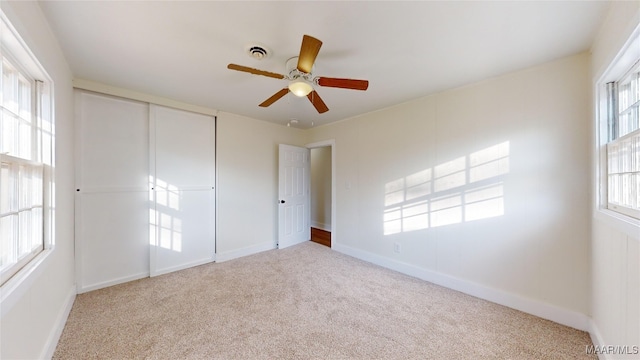 unfurnished bedroom featuring light carpet, ceiling fan, and a closet