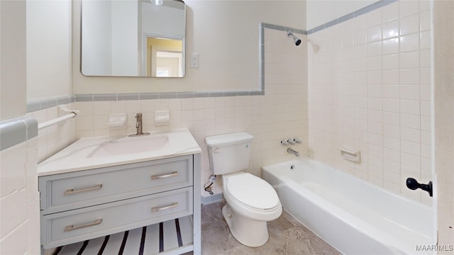 full bathroom featuring vanity, tiled shower / bath combo, tile walls, and toilet