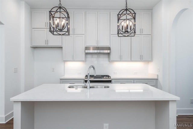 kitchen with a kitchen island with sink, hanging light fixtures, and decorative backsplash