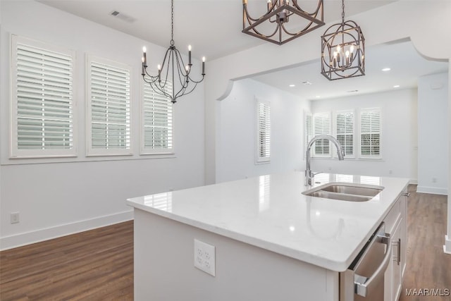 kitchen featuring sink, dark hardwood / wood-style floors, hanging light fixtures, and a center island with sink