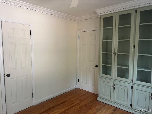 spare room with dark wood-style floors, ceiling fan, ornamental molding, and baseboards