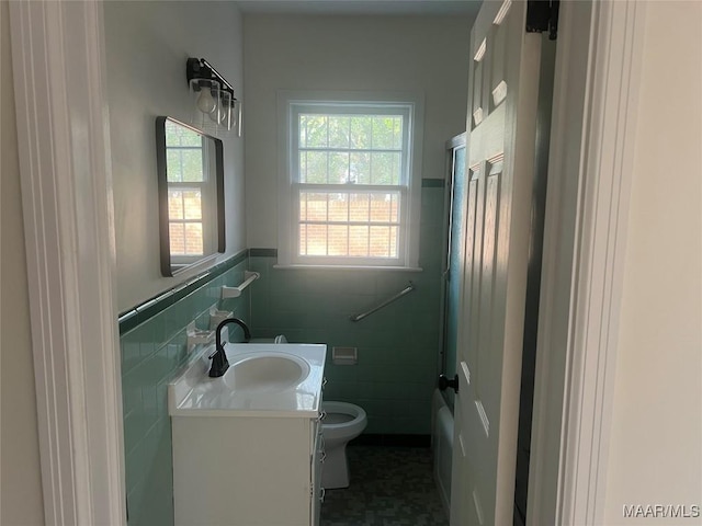 bathroom with tile walls, vanity, toilet, and a healthy amount of sunlight