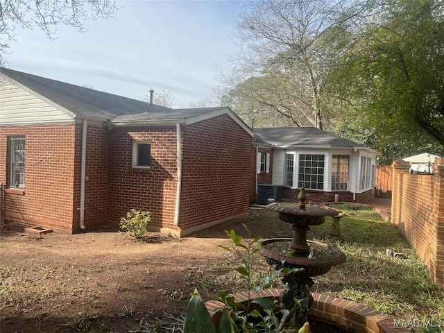 back of house featuring brick siding and fence