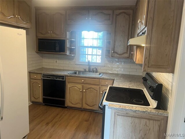 kitchen featuring light wood-type flooring, sink, decorative backsplash, and black appliances