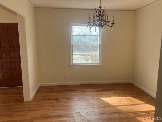 unfurnished dining area featuring a chandelier, baseboards, and wood finished floors