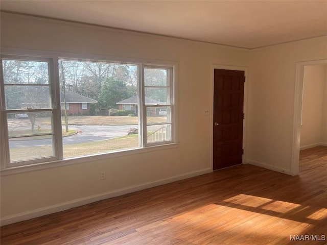 spare room featuring baseboards and wood finished floors