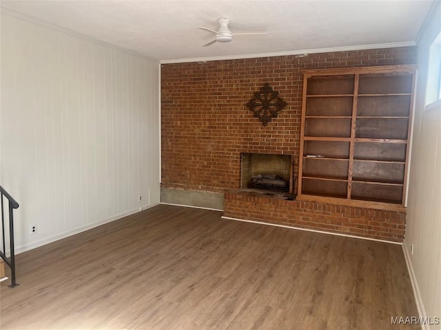 unfurnished living room featuring a brick fireplace, crown molding, and wood finished floors