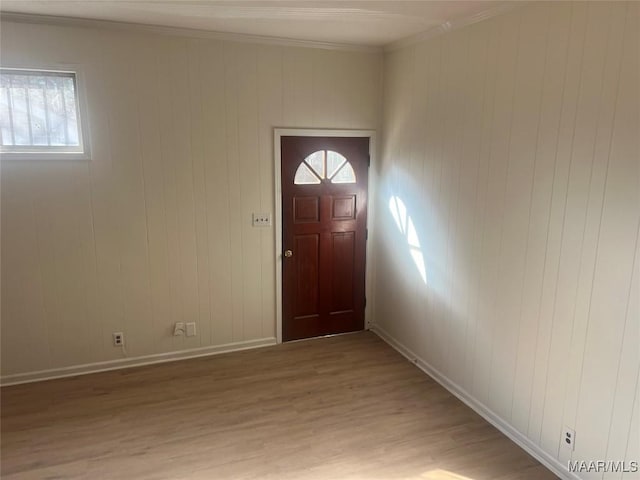 entryway with baseboards, light wood-type flooring, and crown molding