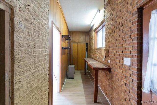 corridor featuring brick wall and light wood-type flooring