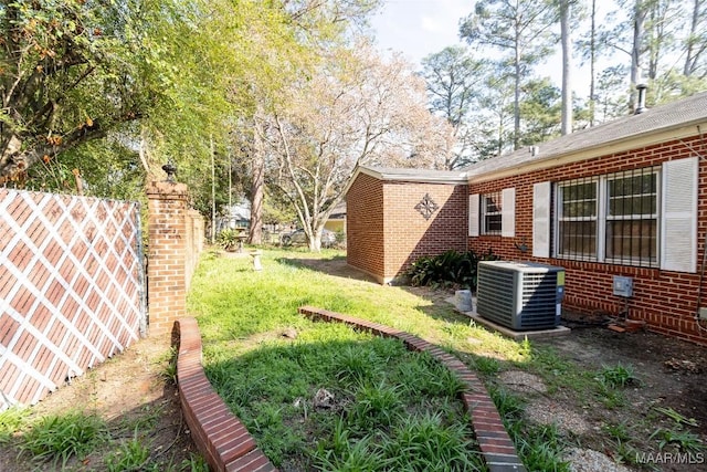 view of yard with central AC and fence