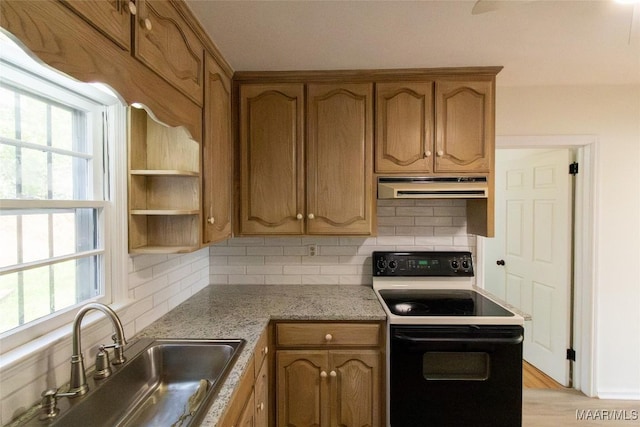 kitchen with a sink, under cabinet range hood, plenty of natural light, and black range with electric stovetop