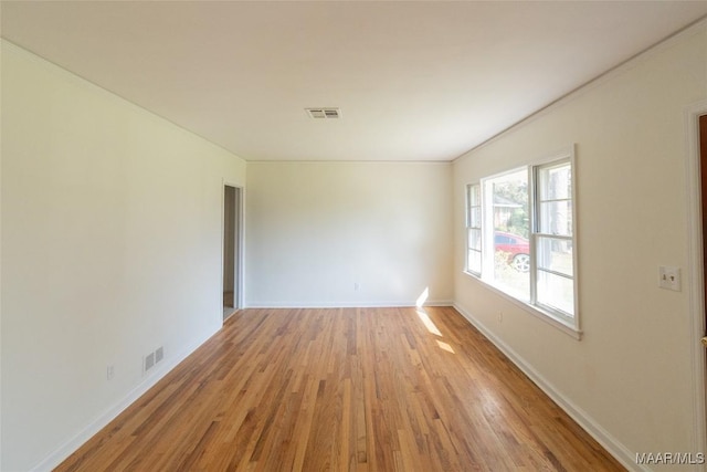 unfurnished room featuring light wood-style flooring, visible vents, and baseboards