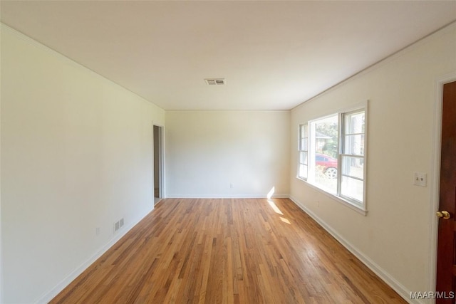 empty room featuring light wood-style floors, baseboards, and visible vents