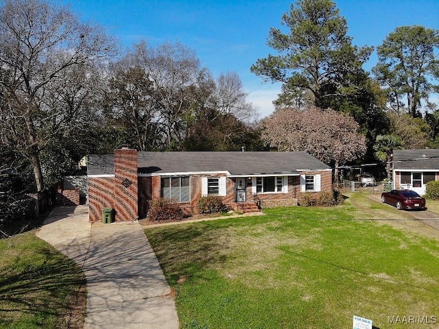 single story home with brick siding, a chimney, concrete driveway, and a front yard