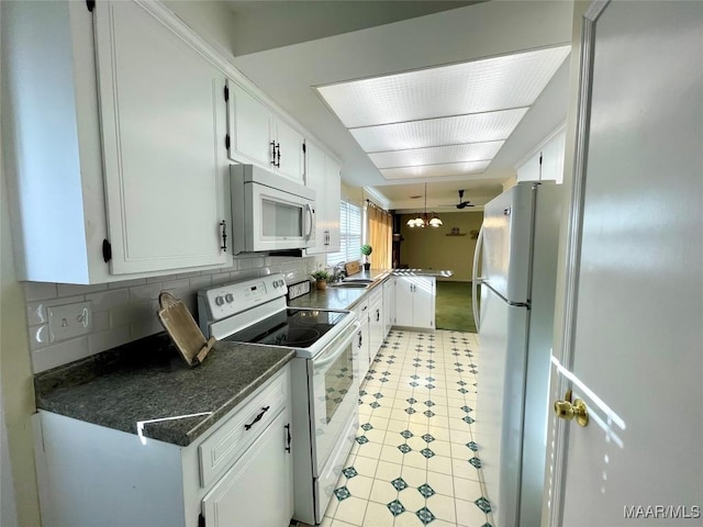 kitchen with backsplash, white appliances, and white cabinets