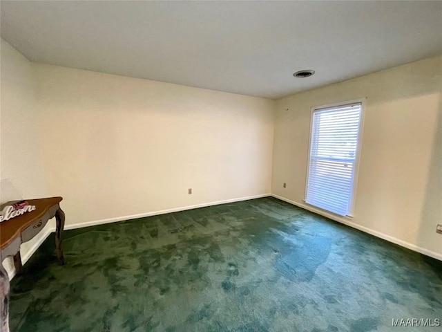 spare room featuring dark colored carpet