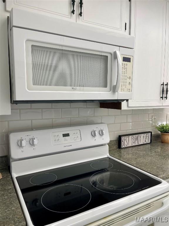 interior details with tasteful backsplash, white appliances, and white cabinets