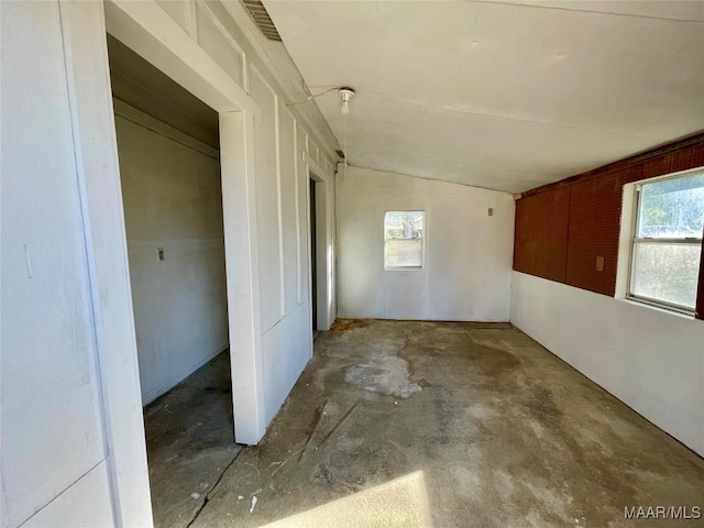 unfurnished room featuring vaulted ceiling and concrete flooring