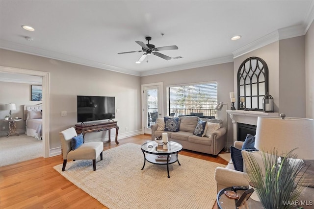 living room featuring ornamental molding, light hardwood / wood-style floors, and ceiling fan