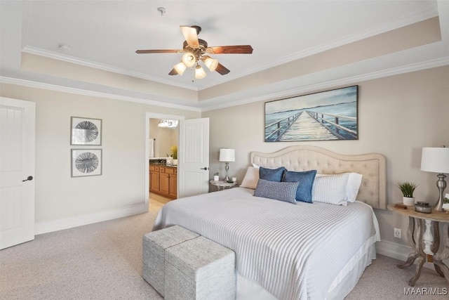 carpeted bedroom with crown molding, ceiling fan, ensuite bath, and a tray ceiling