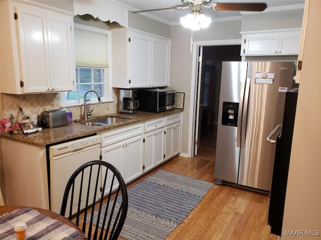 kitchen featuring sink, white cabinetry, crown molding, dark stone counters, and stainless steel appliances