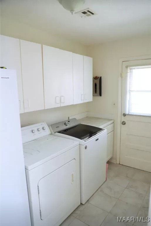 clothes washing area with cabinets and washing machine and clothes dryer