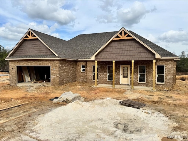 view of front of house with dirt driveway, brick siding, covered porch, and an attached garage