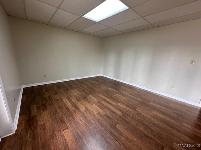 spare room featuring a drop ceiling and dark hardwood / wood-style floors