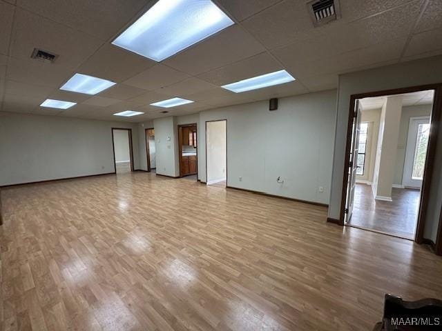 empty room with a drop ceiling and hardwood / wood-style floors