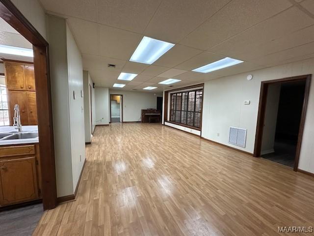 spare room with sink, a paneled ceiling, and light wood-type flooring