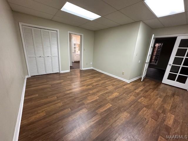 unfurnished bedroom featuring a paneled ceiling and dark hardwood / wood-style flooring