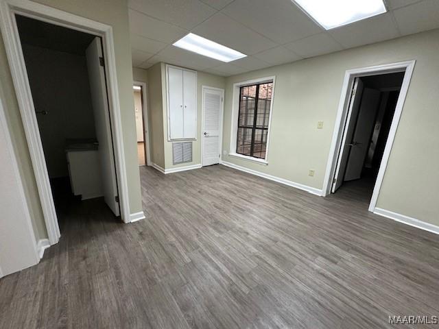 spare room with a drop ceiling and dark hardwood / wood-style floors