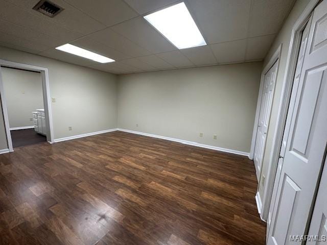 empty room with a drop ceiling and dark hardwood / wood-style floors