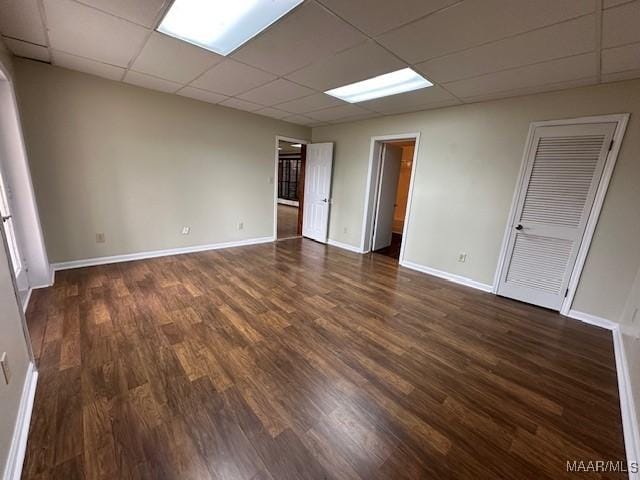 spare room featuring a paneled ceiling and dark hardwood / wood-style floors