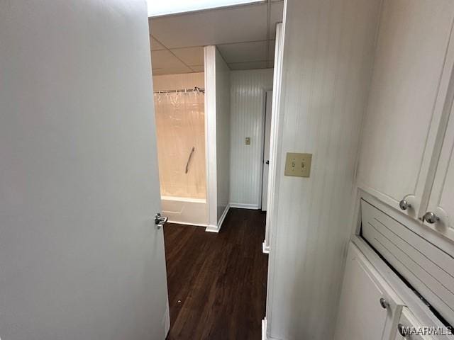 hallway featuring a paneled ceiling and dark hardwood / wood-style floors