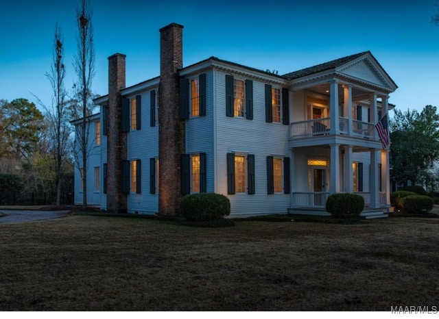 view of side of property with a lawn and a balcony