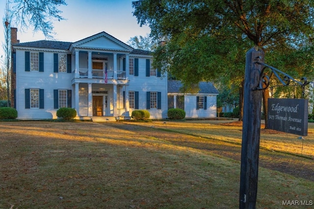 neoclassical / greek revival house featuring a balcony and a front yard