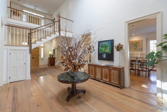 interior space with a towering ceiling and light hardwood / wood-style floors