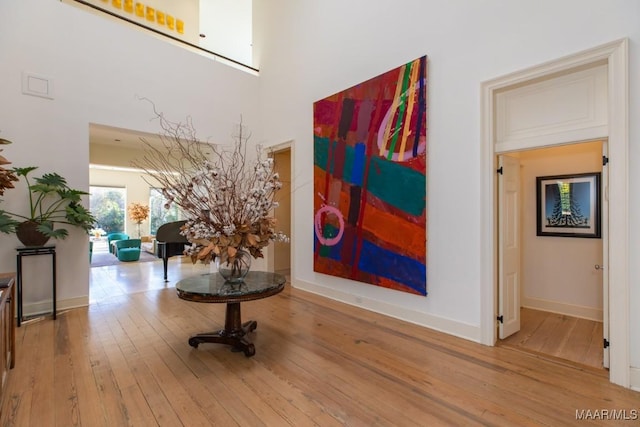 corridor featuring wood-type flooring and a high ceiling